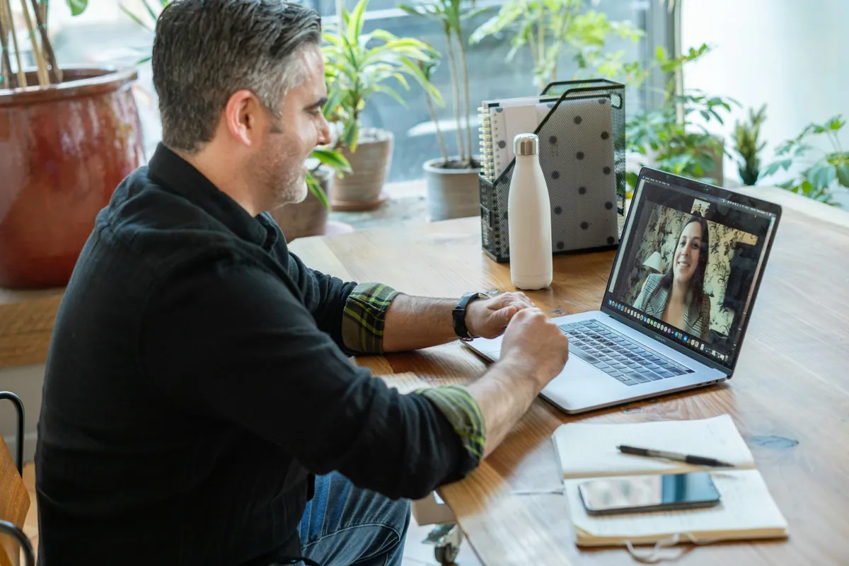 Professionista in videochiamata con una cliente dal laptop, alla sua scrivania