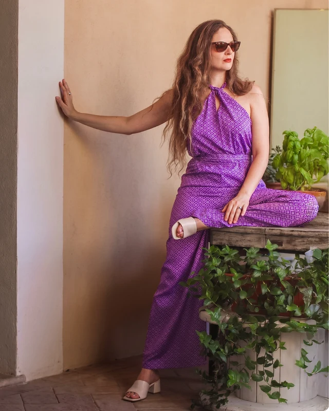 Fotografia di moda: modella in completo viola accanto a una parete color sabbia